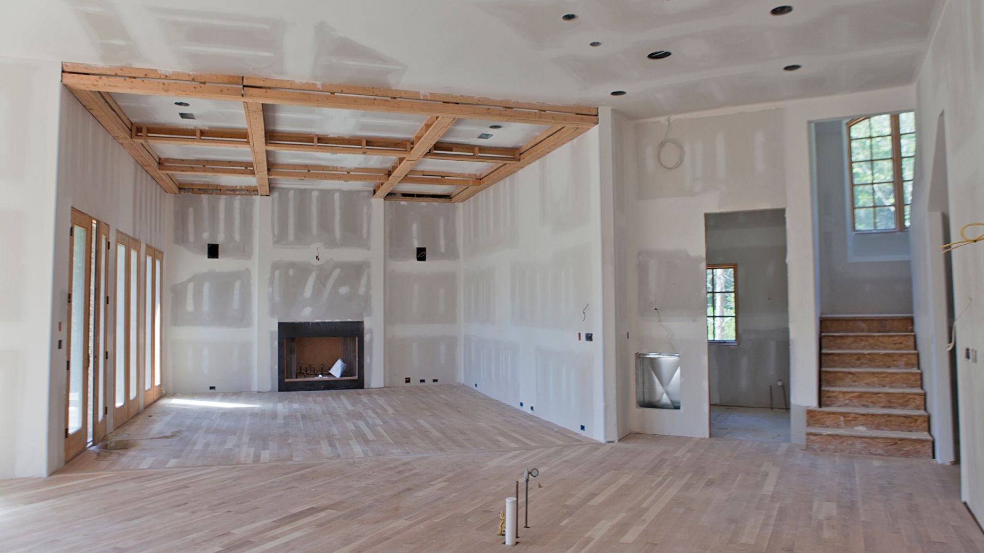 Home interior under construction with drywall, wooden floors, and fireplace