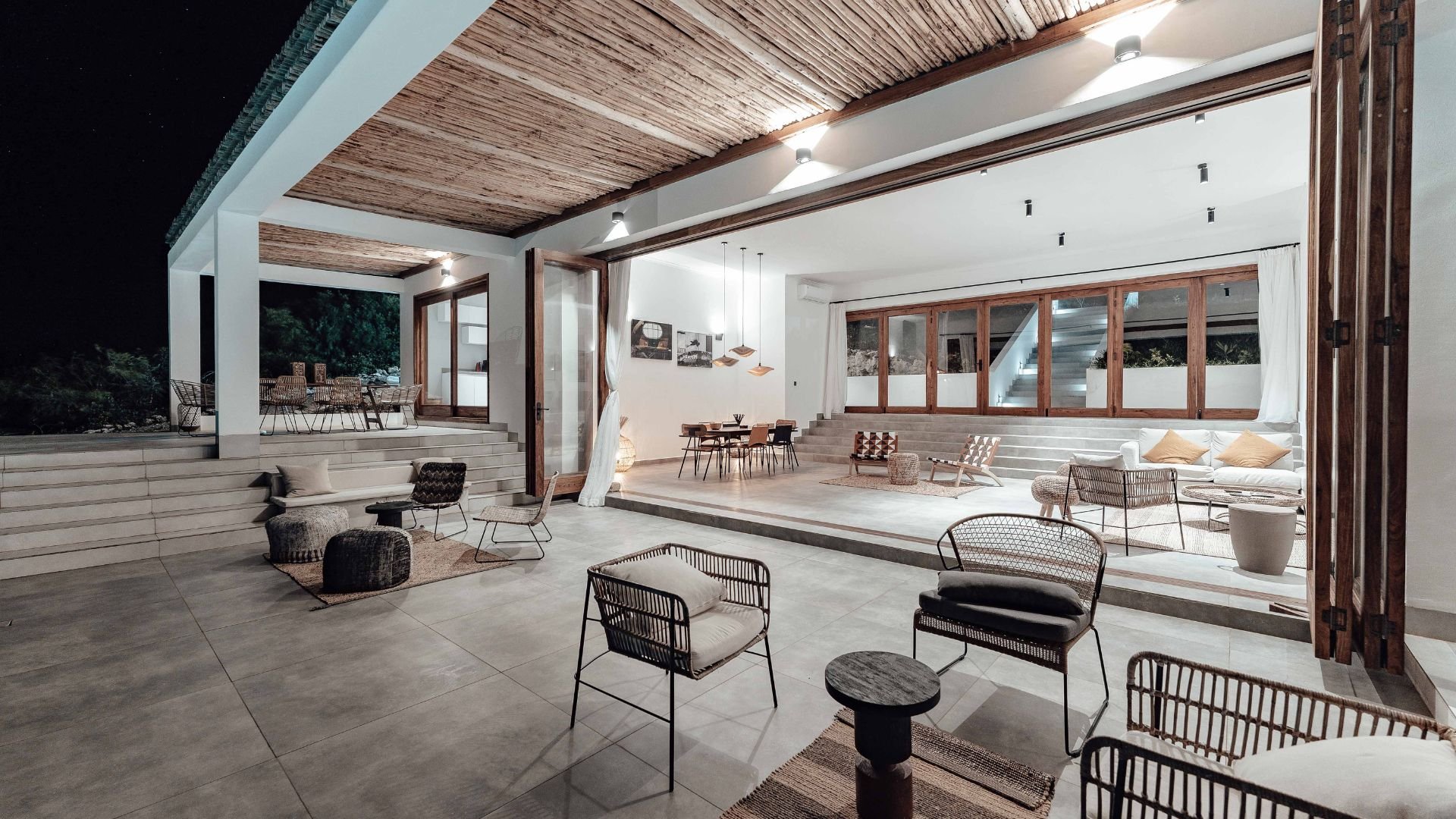 Modern open-plan interior with wooden ceiling, multiple levels, and woven chairs