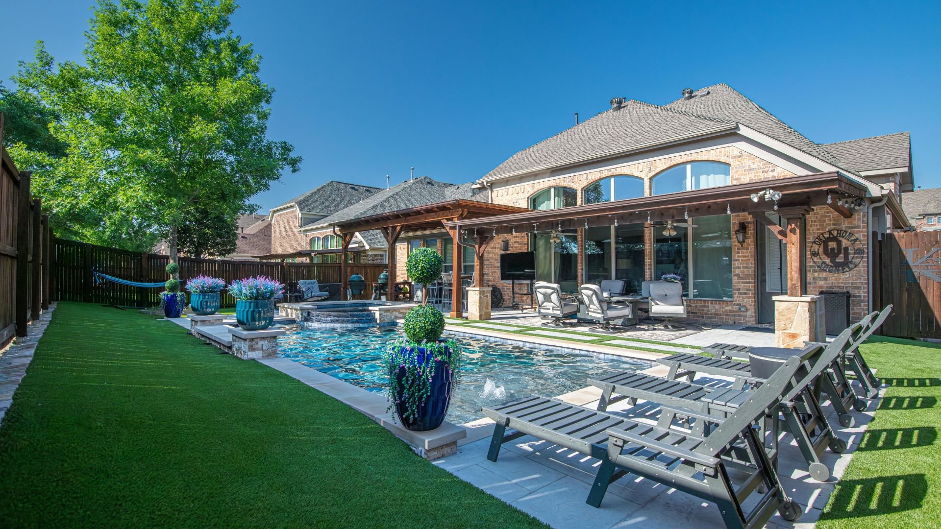 Luxurious backyard with swimming pool, covered patio, and lounge chairs