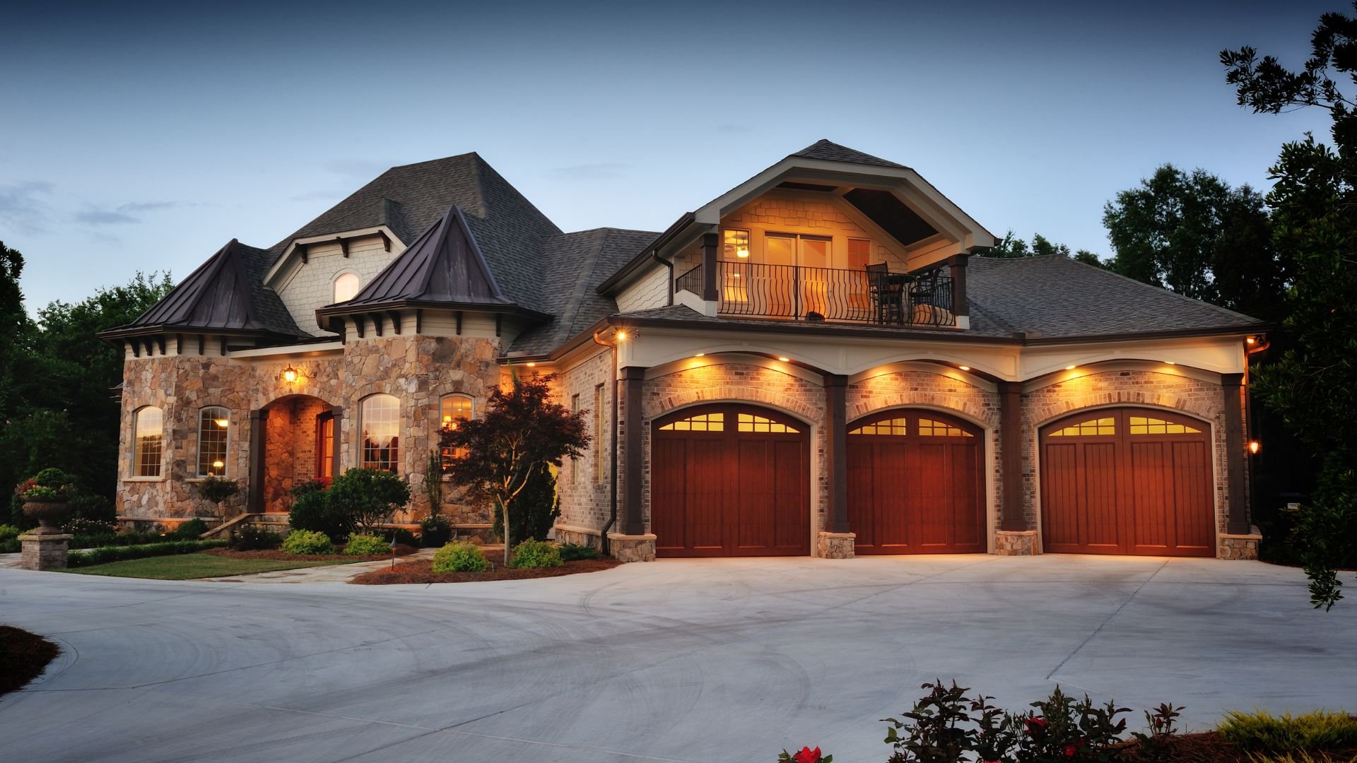 Large stone and brick house with three-car garage at twilight