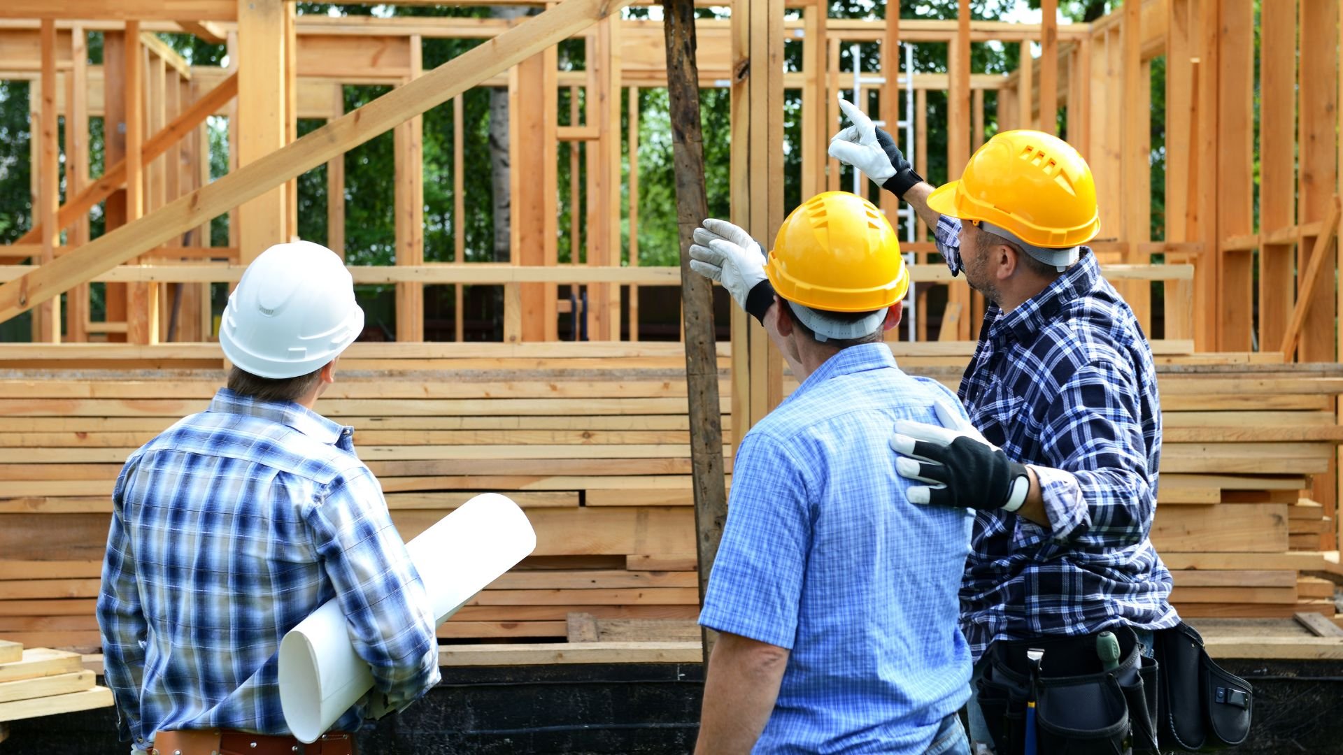 Construction workers in hard hats examining wooden frame of building