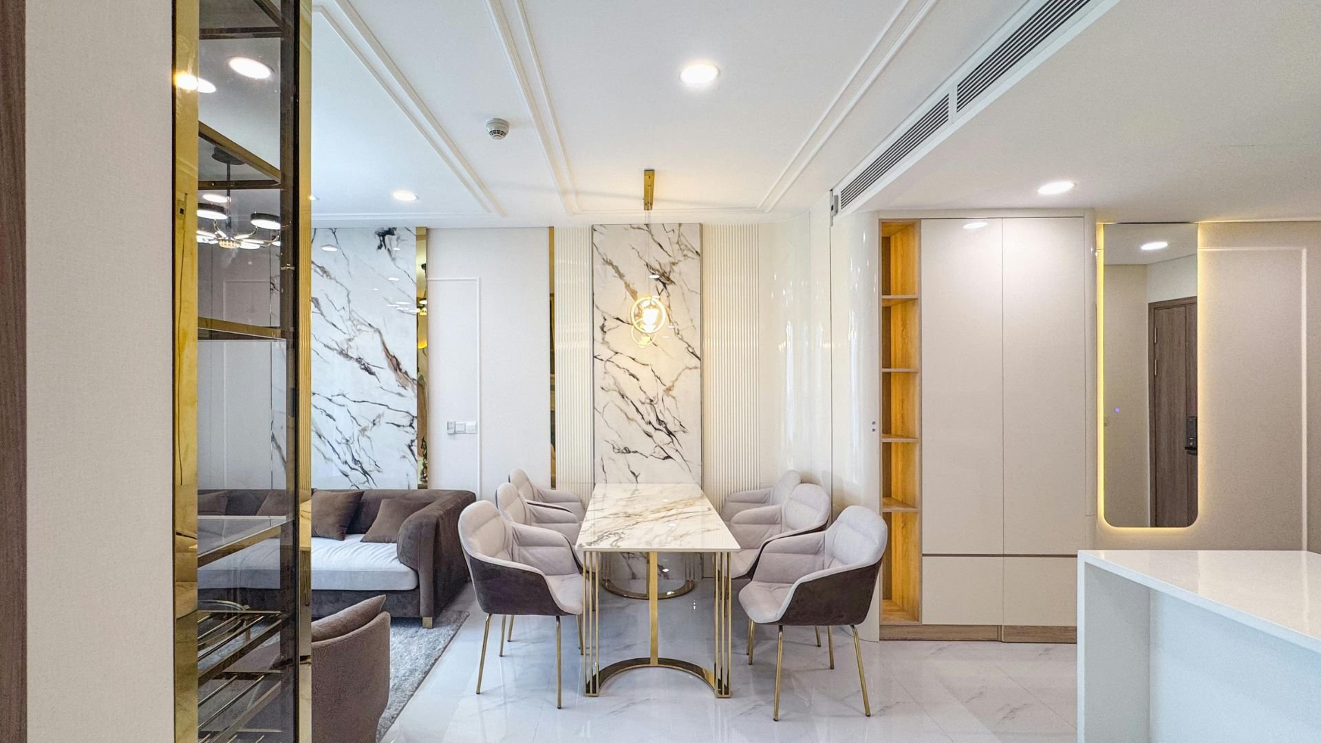 Luxury dining area with marble table, gold accents, and plush grey chairs