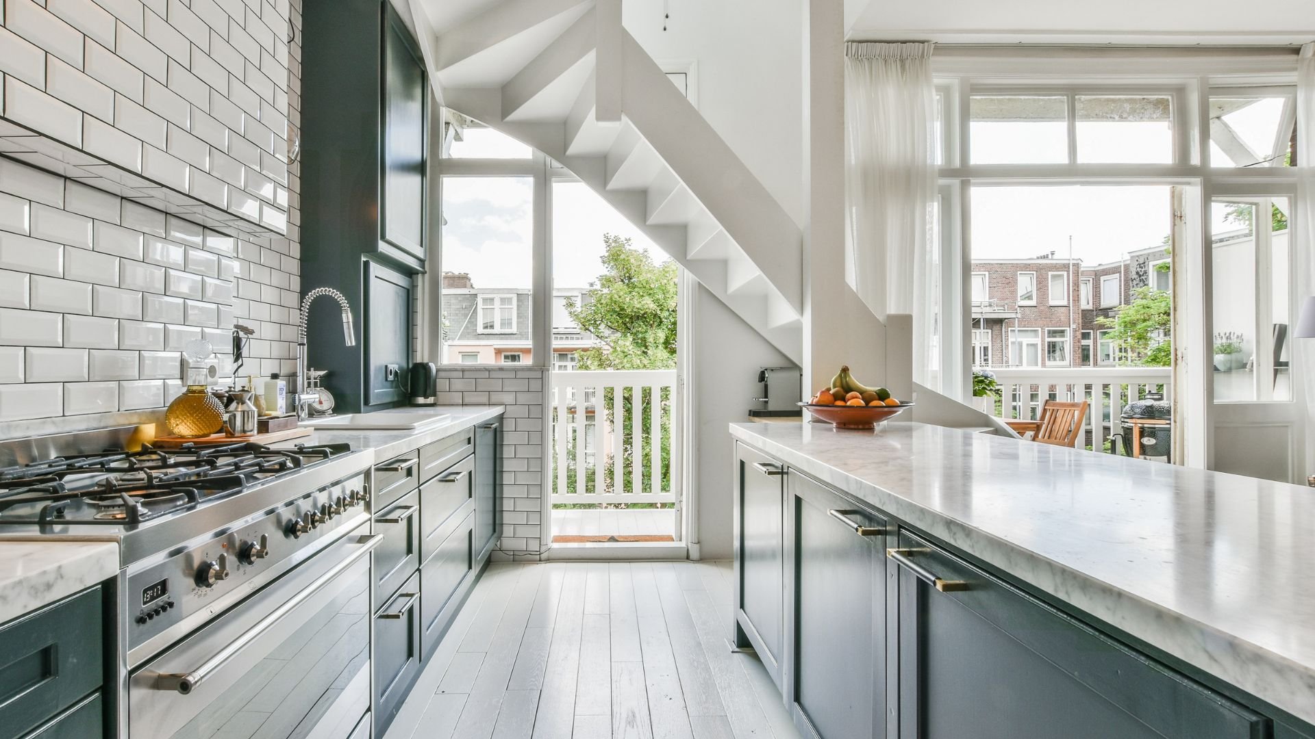 Modern kitchen with white subway tiles, green cabinets, and large windows