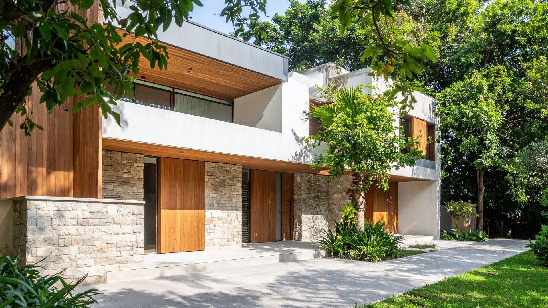 Modern house with wood and stone exterior surrounded by lush green trees