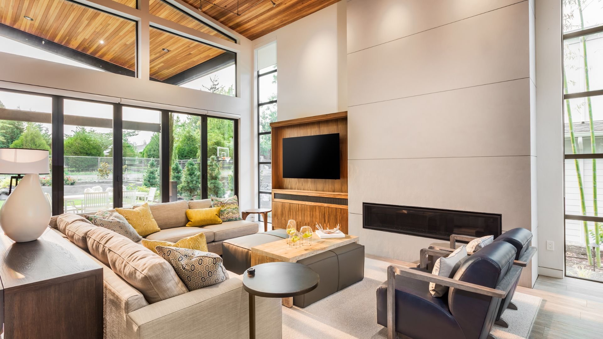 Modern living room with large windows, fireplace, and wood ceiling